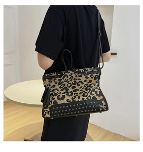 Detail view of leopard print handbag with bottom studs, side tassels and dual handles