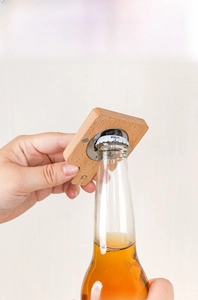 Action shot of the wooden cat paw bottle opener lifting a metal cap off a beer bottle