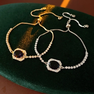 Adjustable pull-chain bracelets in gold and silver with oval purple zircon on green velvet