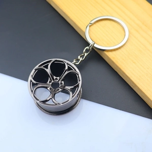 Macro detail of gunmetal car wheel rim keychain with a five-spoke hollow design