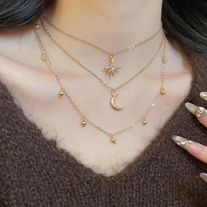 Close-up of layered gold necklace set with sparkling star and moon pendants on a model