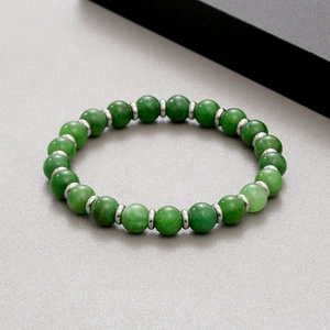 Elastic green agate bead bracelet with silver spacers on grey textured background