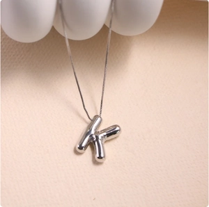 Macro shot of silver letter K balloon style pendant with polished finish on box chain