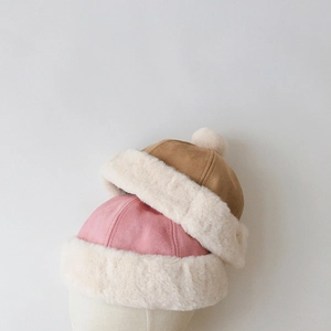 Detail of suede winter beanies in pink and khaki featuring thick faux fur trim and pompom