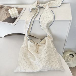 Détail du sac cabas en toile à pois avec une bandoulière décorative à nœud bleu ciel