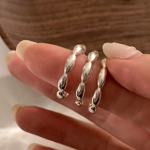 Primer plano de tres anillos apilables de plata con un diseño ovalado de cuentas minimalista