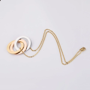 Detailed view of tricolor interlocking rings in gold, rose gold, and silver on a thin chain