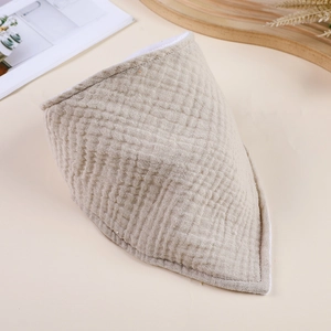 Detail view of a beige double-layer gauze baby bib with soft wrinkled fabric texture