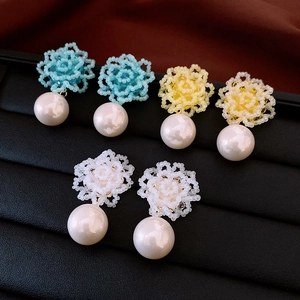 Detailed macro view of colorful beaded flower earrings with pearls in a black velvet jewelry box