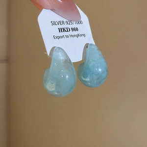 Detailed view of light blue teardrop resin earring with marble texture on silver needle