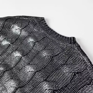 Gros plan détaillé d'un pull gris foncé en maille torsadée avec finition dorée mate