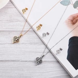 Detail of gold and silver heart jewelry set featuring wavy textures on a wooden surface