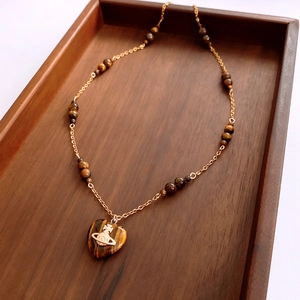 Detail of tiger eye heart pendant with golden orb logo on beaded necklace