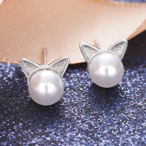 Detail of silver cat-ear earrings with white faux pearls on elegant ribbon background