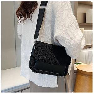 Detail of plush lamb wool and leather patchwork crossbody bag on a model wearing a white sweater