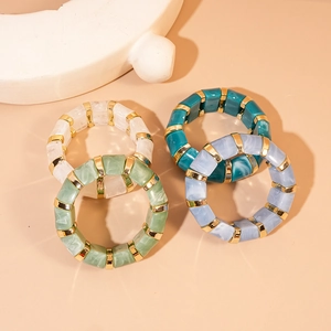 Detail of marble pattern resin bracelets with gold metal spacers on warm background
