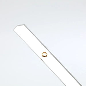 Polished gold circular metal ring displayed on minimalist acrylic stand