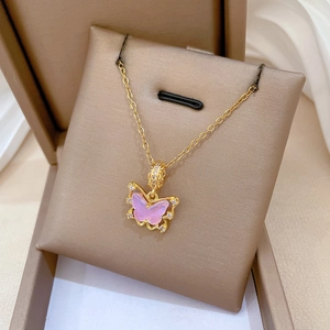 Détail d'un collier papillon doré avec des ailes en zircone rose sur un présentoir