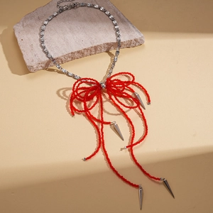 Crystal beaded bow pendant necklace with silver spikes on a textured stone background