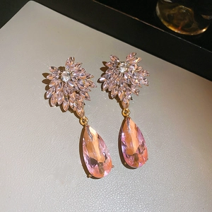 Gros plan de boucles d'oreilles gouttes roses avec cristaux facettés et pendentifs en poire