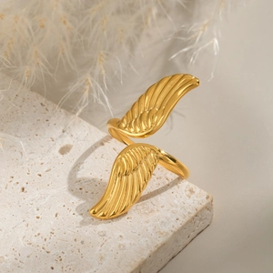 Minimalistischer 18K vergoldeter Edelstahlflügelring offen auf einem Steinsockel