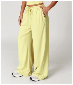 Detail of light yellow wide-leg drawstring pants with elastic waist and side pockets