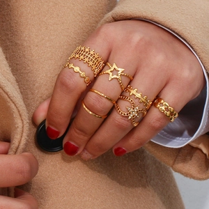 Close-up of gold bohemian ring set with woven patterns and star details on hand