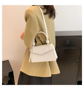 Petit sac blanc texturé porté avec un blazer olive pour un style chic et urbain