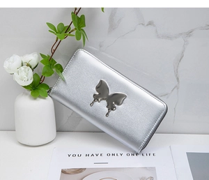 Detail of silver long wallet with metallic butterfly ornament and zip closure on marble
