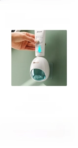 Detail of automatic wall-mounted toothpaste dispenser with green press port on white base