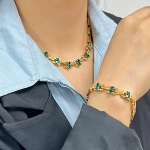 Detail of 18K gold-plated necklace and bracelet set featuring sparkling green zircons