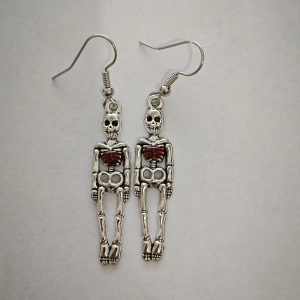 Detailed macro view of Gothic skull earrings with red heart accent and silver hooks