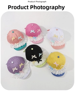 Flat lay of colorful children's baseball caps with lace trim and ribbon bow decorations