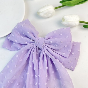 Macro detail of lavender purple chiffon bow hair clip with textured polka dots