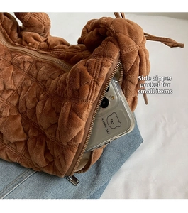Detail of side zipper pocket on a brown quilted plush dumpling bag for smartphone storage