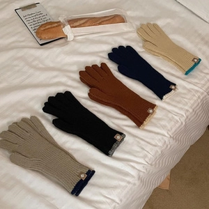 Flat lay of colorful knit touchscreen gloves in beige, black, brown and navy on white bedding