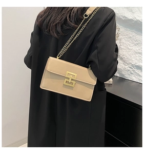 Detail of minimalist beige shoulder bag featuring a gold square lock and chain strap