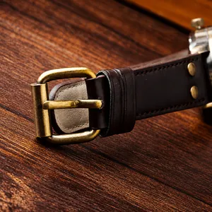 Macro detail of vintage dark brown leather watch strap with bronze buckle and rivets