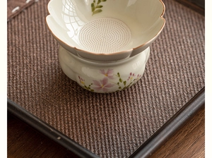 Detailed top view of ceramic tea strainer with hand-painted daisy pattern and fine filter holes