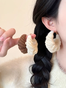 Gros plan sur les créoles faites à la main en laine crochetée beige et marron
