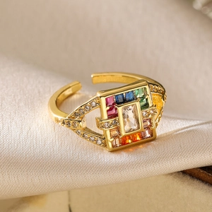 Detailed close-up of gold-plated ring with colorful zircons on champagne silk