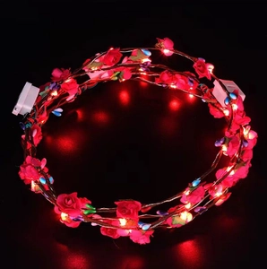 Detail showing the red LED rose headband with glowing lights and battery box on black background