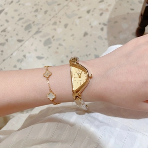 Gros plan détaillé d'une montre à quartz triangulaire dorée et d'un bracelet trèfle élégant