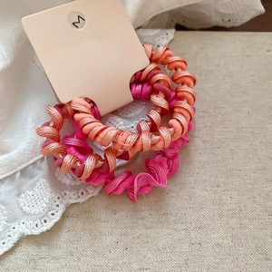 Détail de trois élastiques à cheveux roses avec tissage en spirale sur carte
