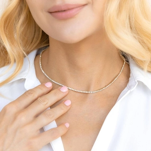 Minimalist single row rhinestone necklace in gold finish worn by model on neck