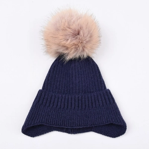 Detailed view of dark blue ribbed knit winter hat with a large detachable fluffy fur pompom