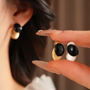 Minimalist oval stud earrings in matte gold and silver with black high-gloss accents