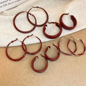 Flat lay of Ancora red enamel twisted hoop earrings on vintage textured paper background
