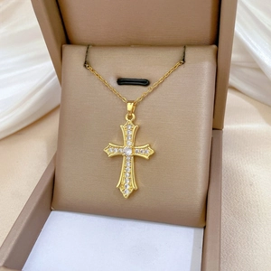 Macro detail of gold cross pendant with sparkling zircons inside a luxury gift box