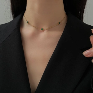 Close-up of elegant gold necklace with square green zircons worn on a model's neck